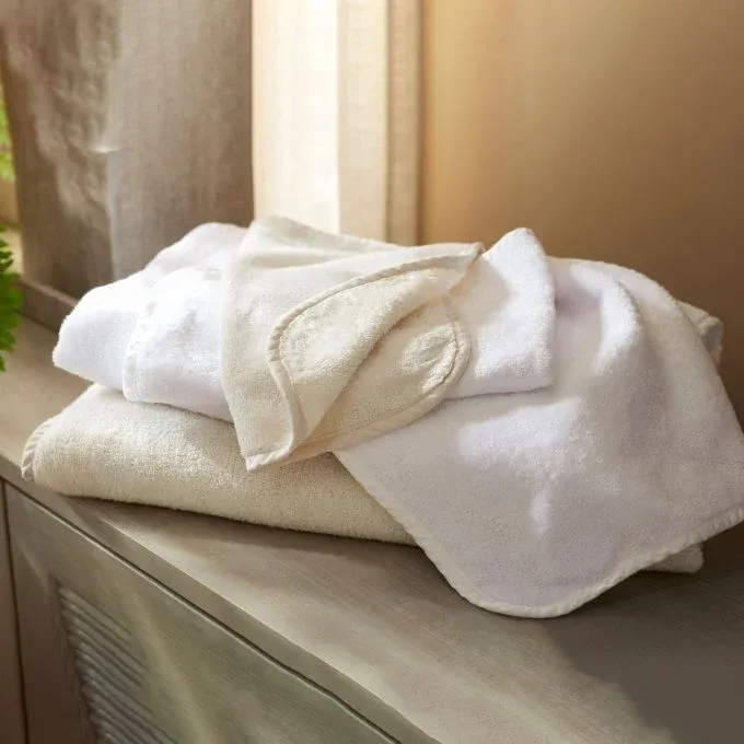 Legna Terry ivory and white cotton washcloth set folded on a wooden dresser.