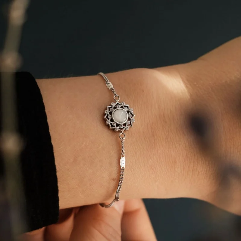 Silbernes Armband mit rundem grauem Cabochon im Blütenornament und feiner Kette.