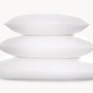 Matouk Montreux three white duck down pillows stacked by size on white background.
