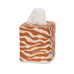 The Matouk Regine | Linen Jacquard Tissue Box Cover is a square box featuring an orange and white zebra motif, with one tissue visible at the top.