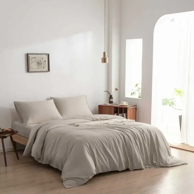 Bamboo duvet cover in Soft Taupe styled on a bed in a bright bedroom with a hanging pendant light and arched window