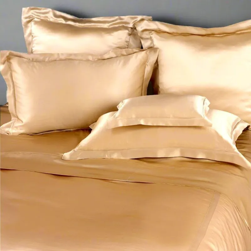 Kumi Kookoon champagne silk pillow shams and bedding arranged on a made bed.